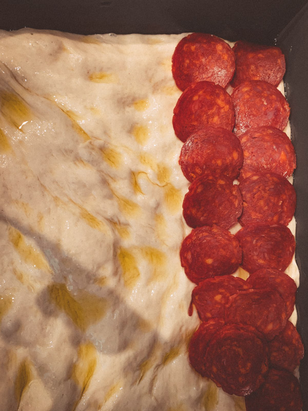 Over head view of Detroit style pizza showing layering of pepperoni.