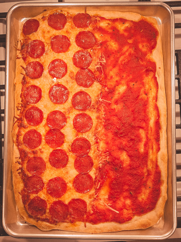 Overhead of cooked Roman style pizza, half cheese and pepperoni and half sauce only.