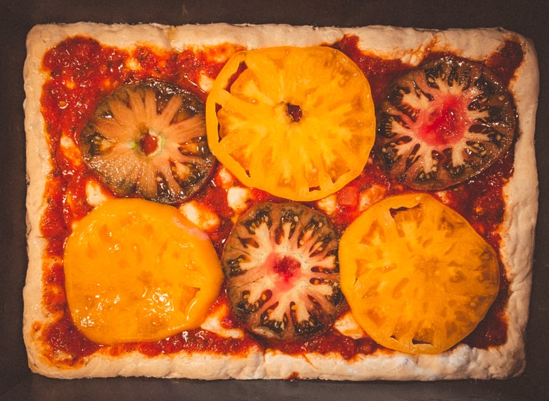 Pizza before baking with multi-color heirloom tomatoes.  