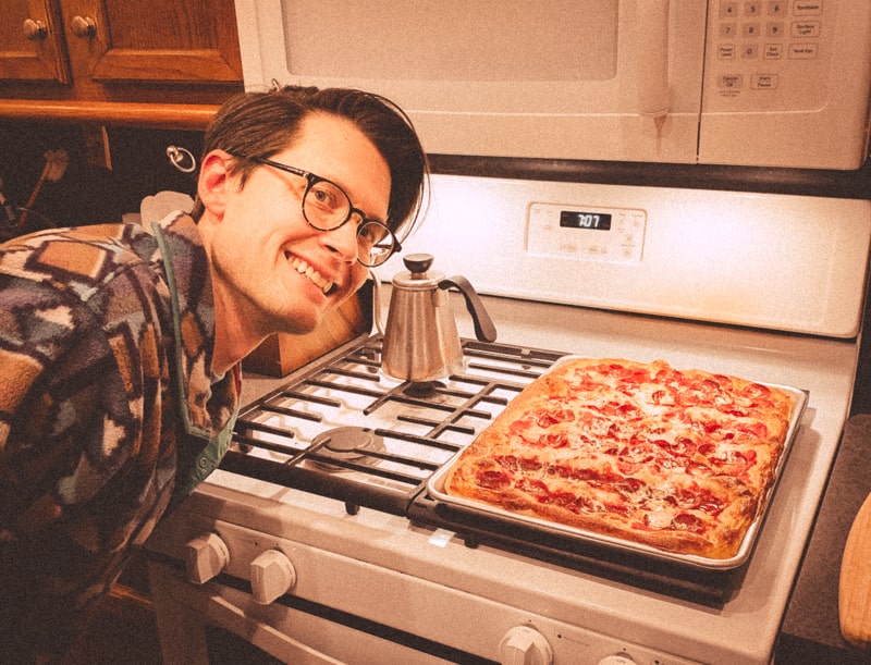 The author smiling next to a pizza. 