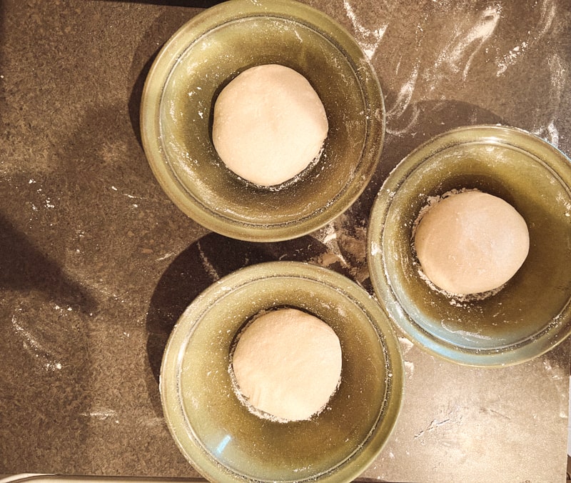 Pizza dough balls in bowls.